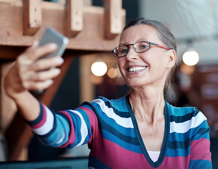 woman taking a selfie with a new full-arch implant-supported denture