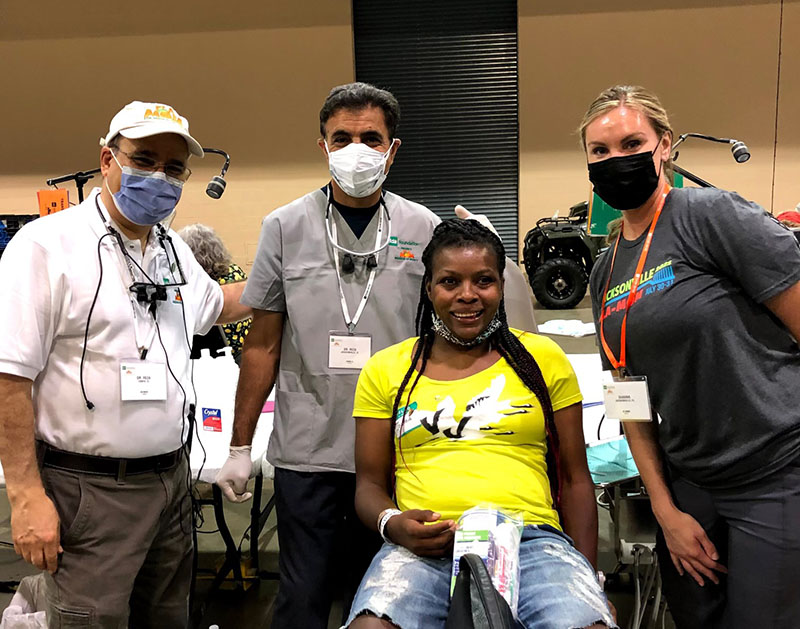 Dentists at a charity event where they help fix teeth for economically disadvantaged persons - With patient who looks happy.