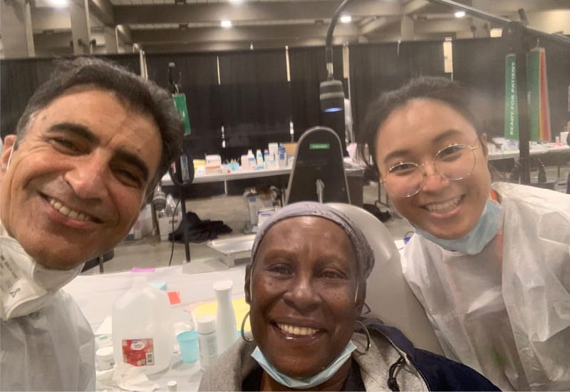 Dentists at a charity event where they help fix teeth for economically disadvantaged persons - With patient who looks happy.