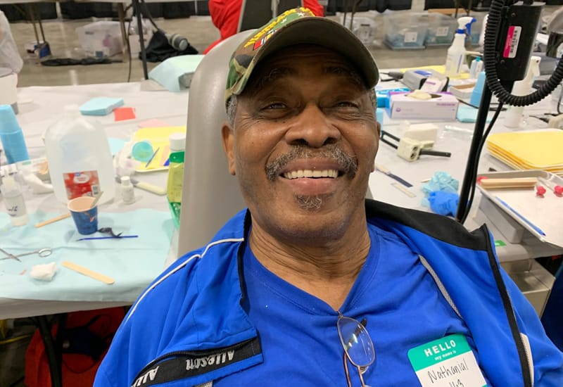 Dentists at a charity event where they help fix teeth for economically disadvantaged persons - With patient who looks happy.